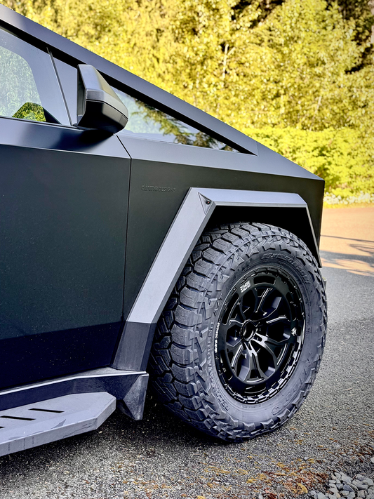 Close-up of a modern vehicle's wheel and fender on a road with trees in the background