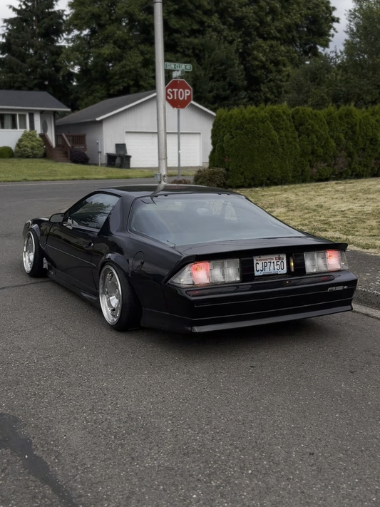 Black sports car on a residential street with a stop sign in the background