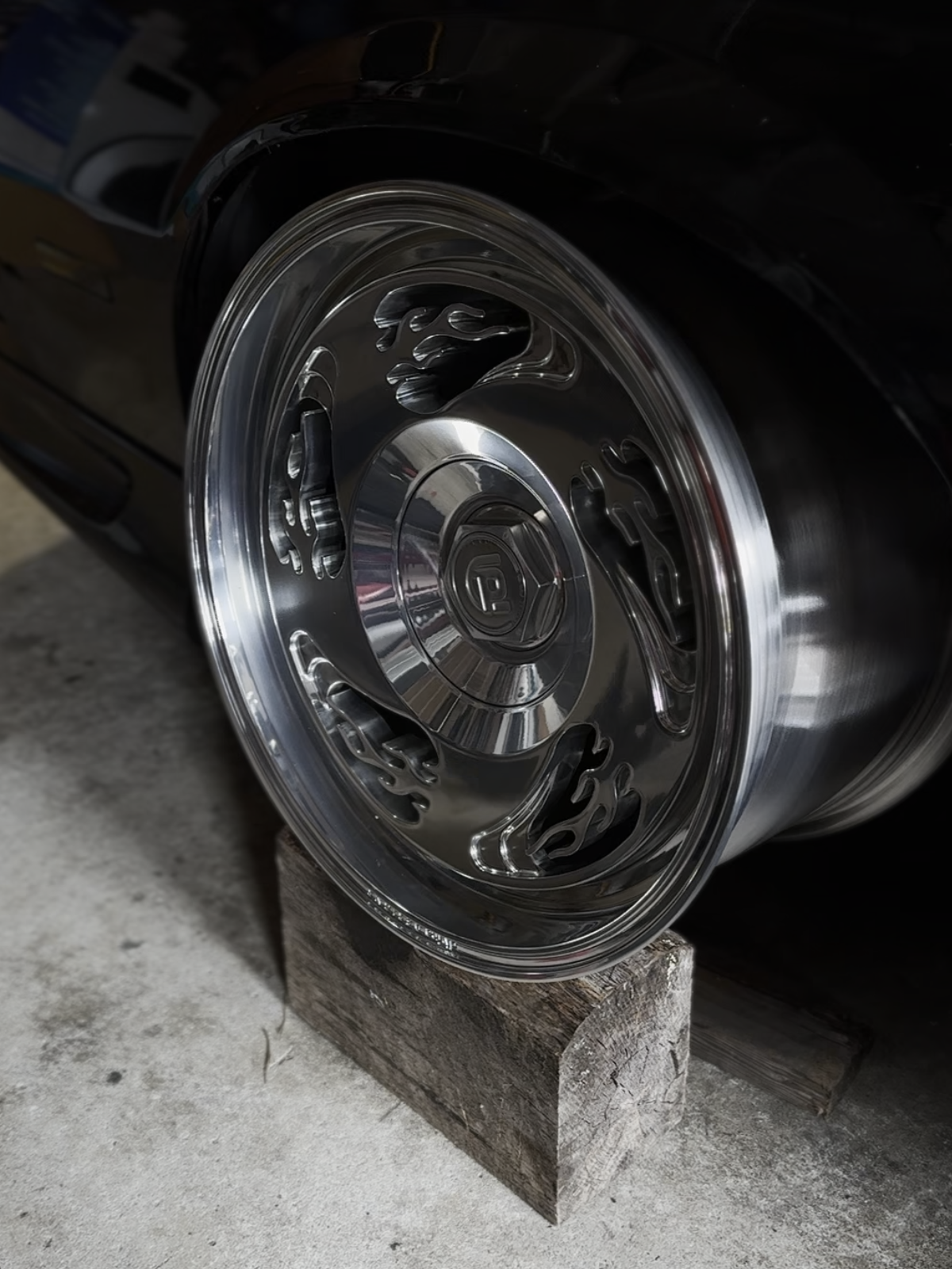 Close-up of a car wheel with flame design on a concrete surface