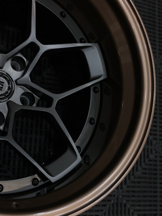 Close-up of a car wheel rim with a detailed design on a textured black background