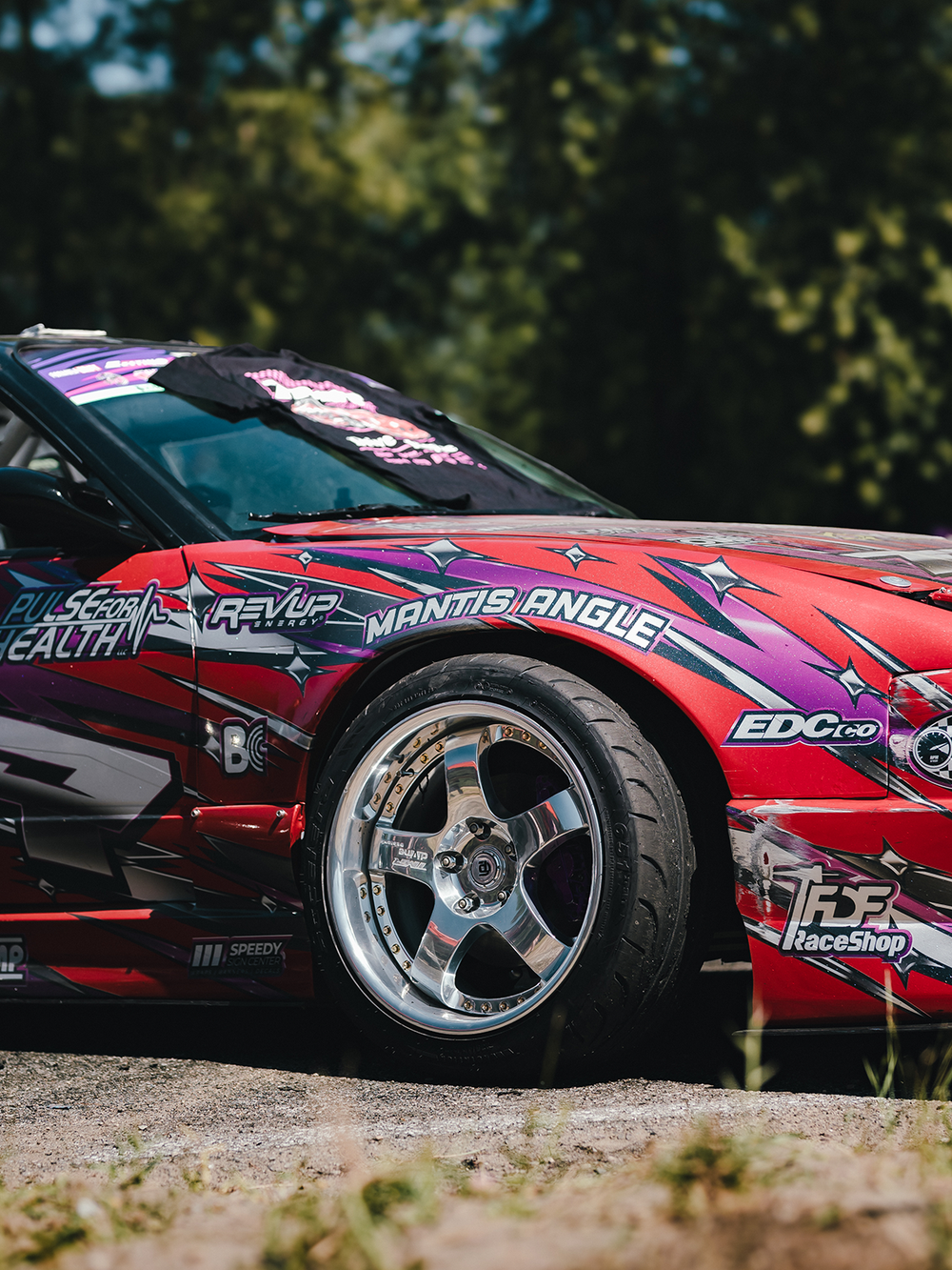 Red and black race car with various sponsor logos on a dirt track