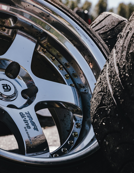 Close-up of a shiny chrome car wheel with a blurred background