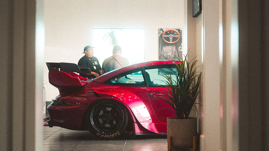 Red sports car in a showroom with people around