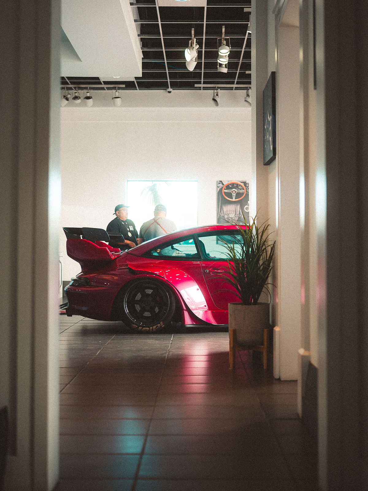 Red sports car in a showroom with people around