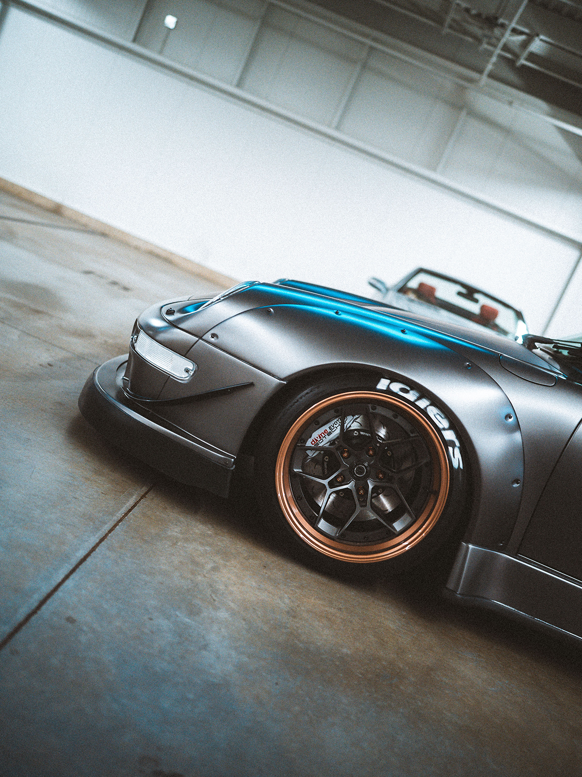 Silver sports car with a blue accent in a garage
