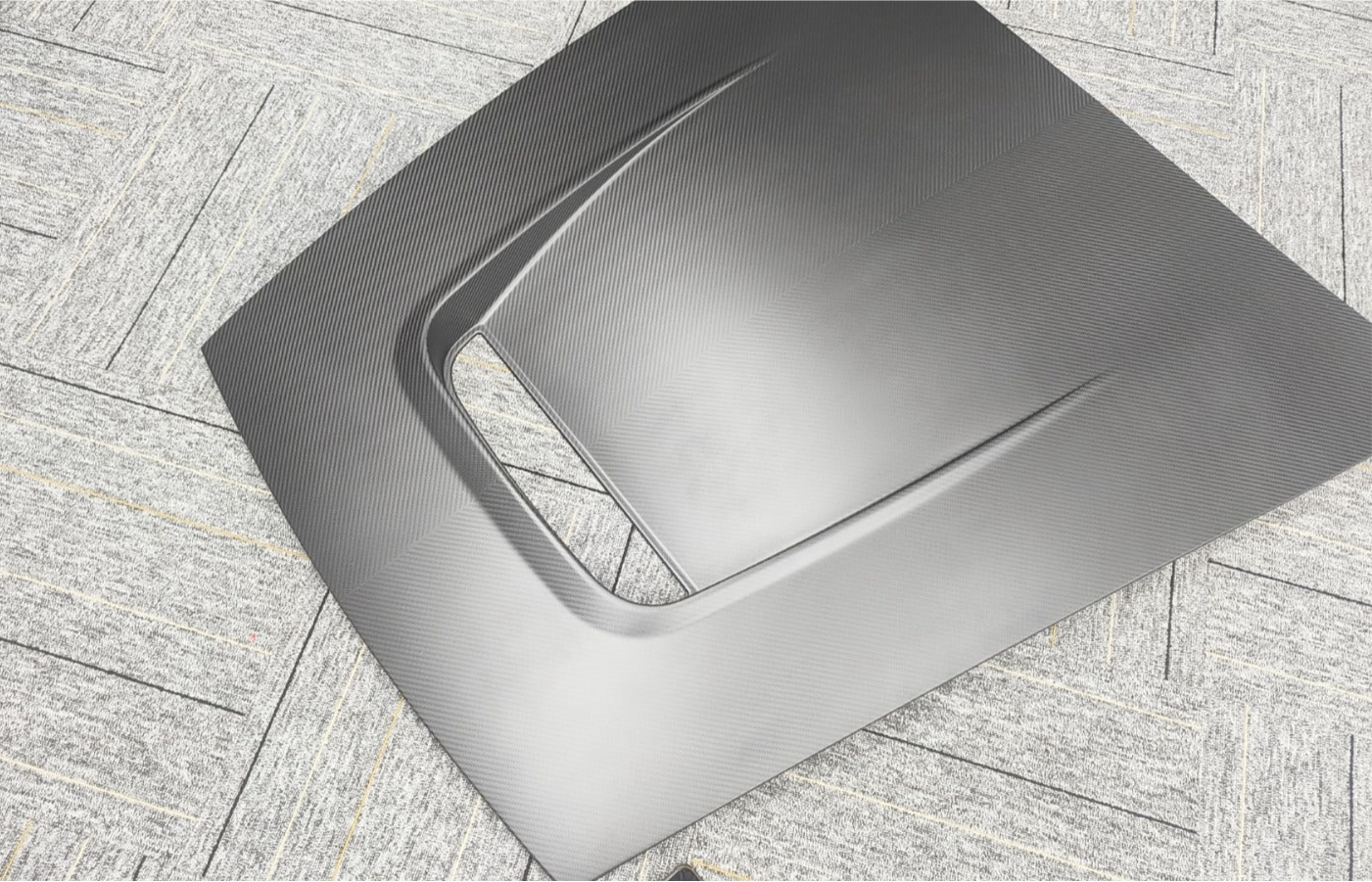 Carbon fiber hood on a textured gray surface