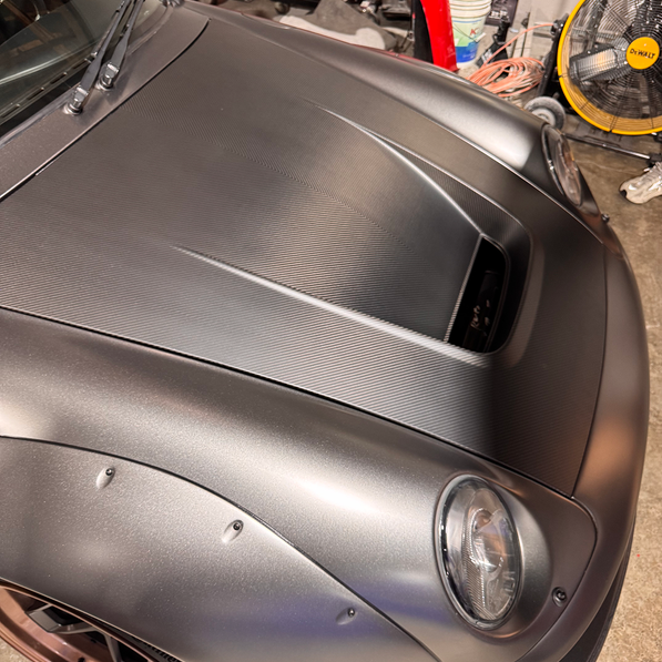 Close-up of a silver car's hood in a garage setting