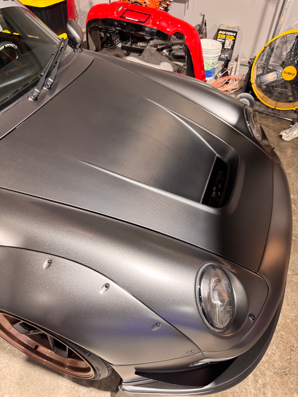 Close-up of a silver car's hood in a garage setting