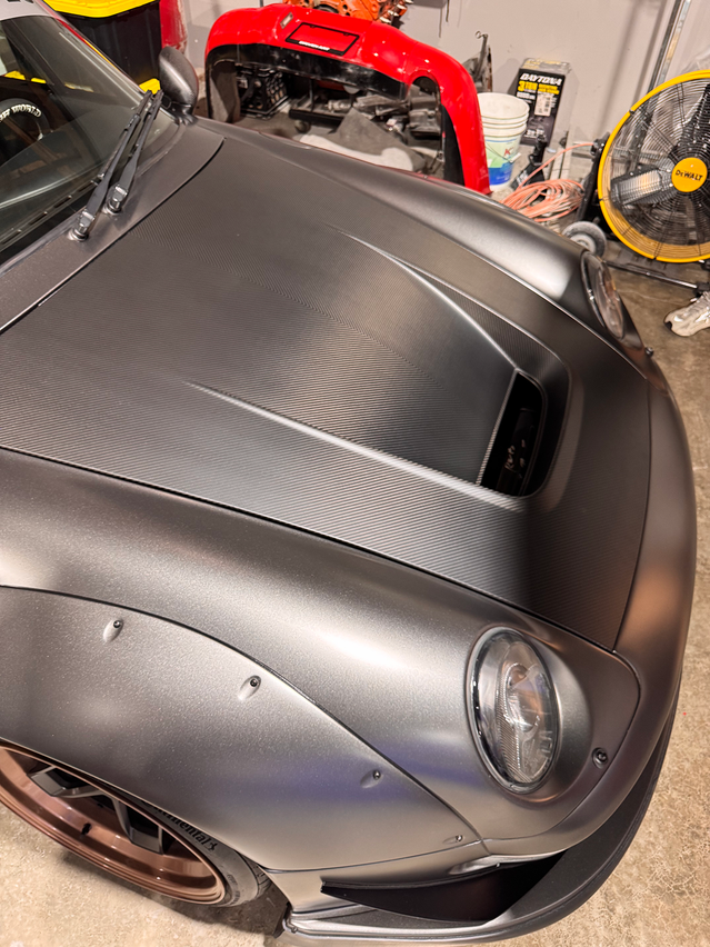Close-up of a silver car's hood in a garage setting