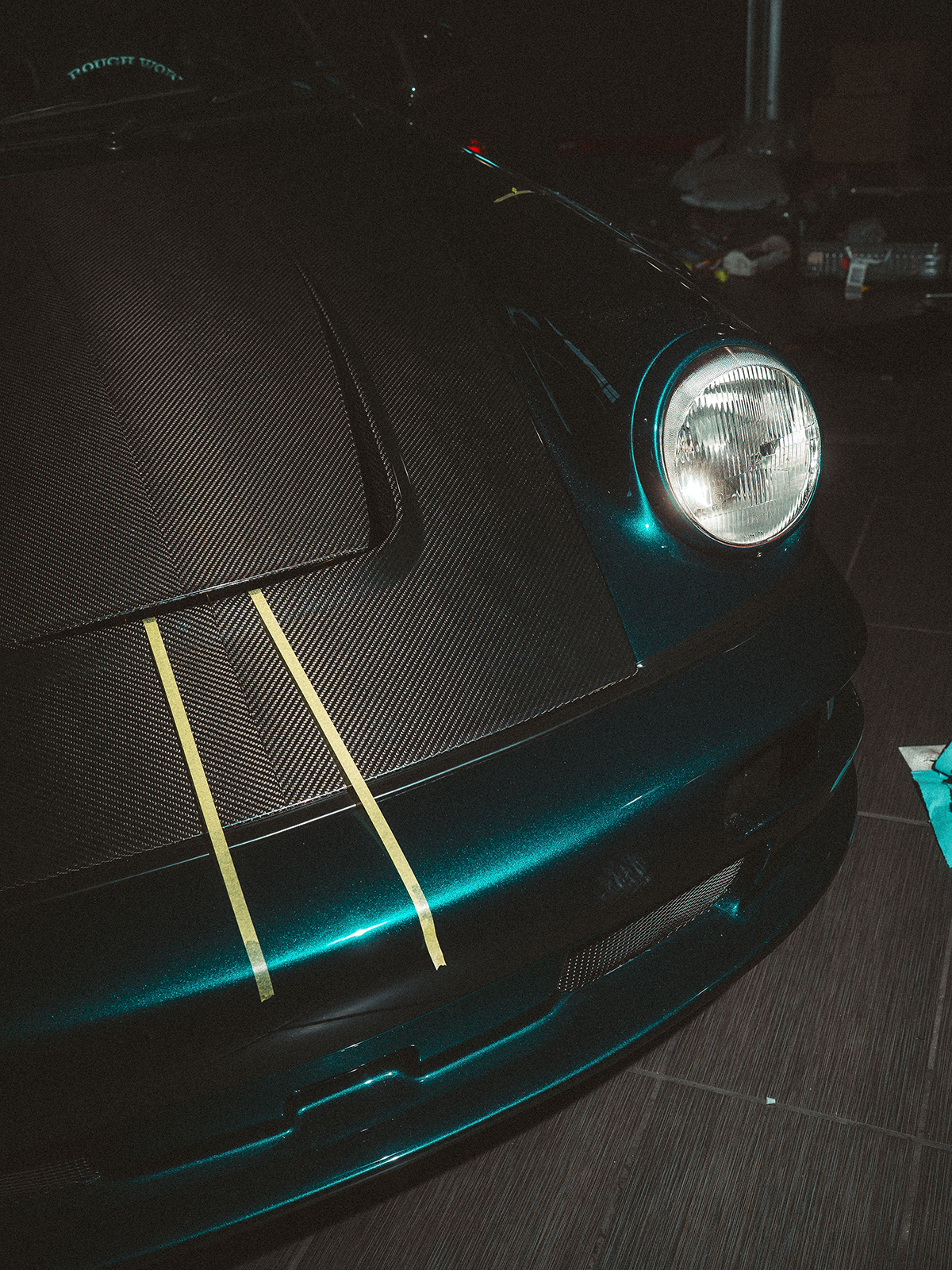 Close-up of a blue Porsche with carbon fiber hood on a dark background
