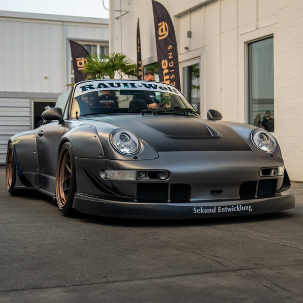 Modified Porsche car with 'Rauh-Welt' branding in front of a building.