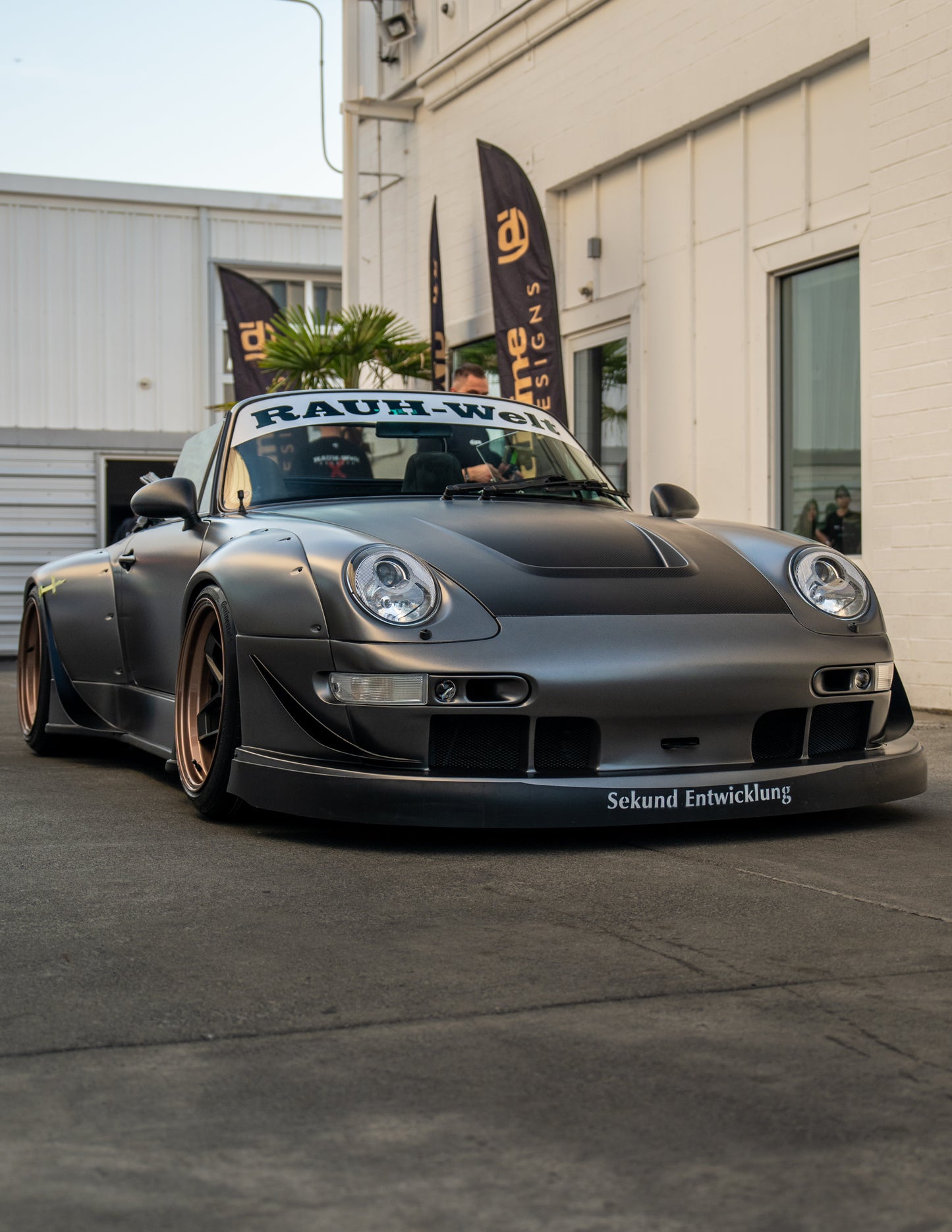 Modified Porsche car with 'Rauh-Welt' branding in front of a building.