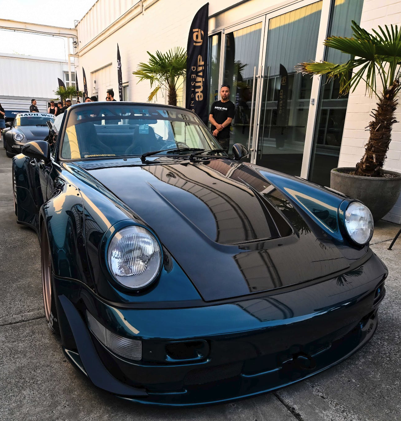 Blue sports car parked in front of a building with palm trees