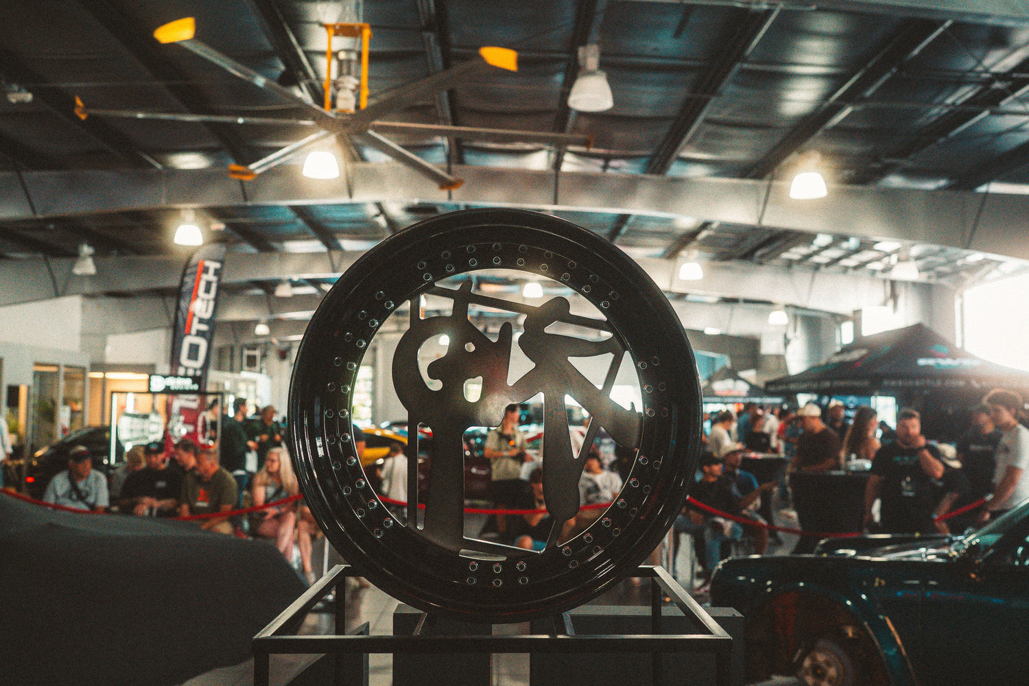 Large wheel with a brand logo on display in a busy indoor setting