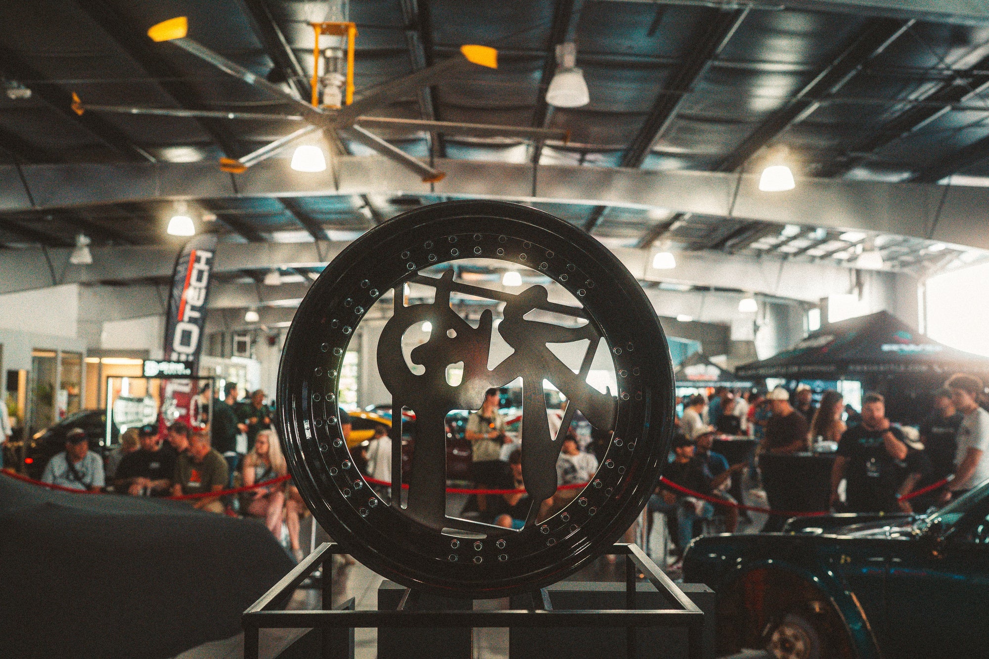 Large wheel with a brand logo on display in a busy indoor setting