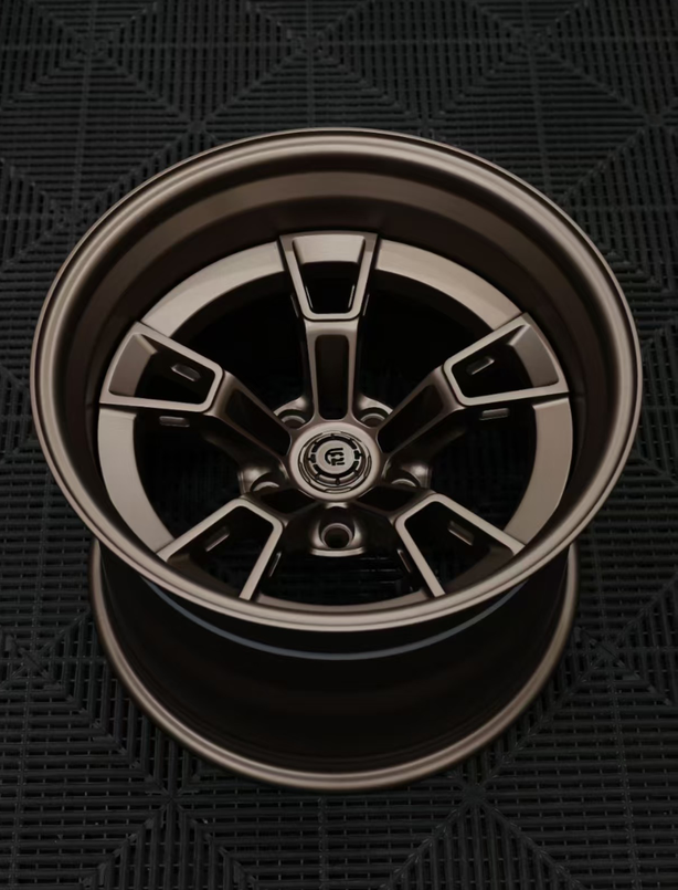 Close-up of a metallic car wheel rim on a dark textured background