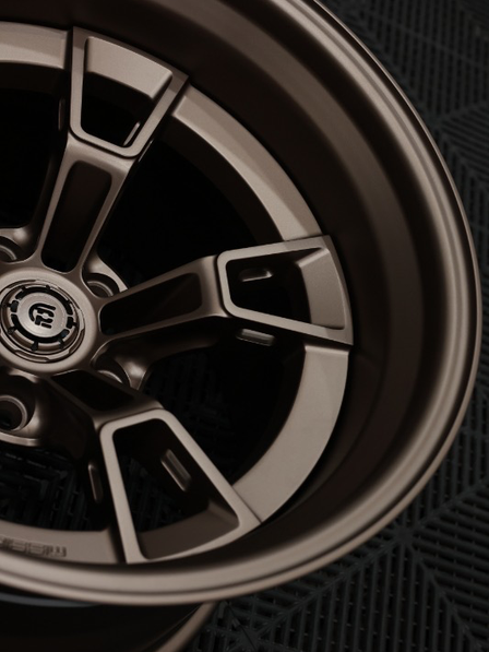 Close-up of a car wheel with a detailed rim design on a textured black background