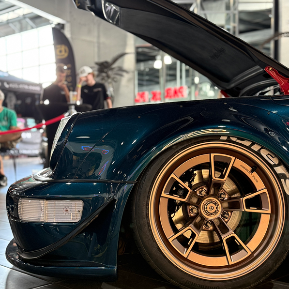 Close-up of a teal car with gold rims in an indoor setting