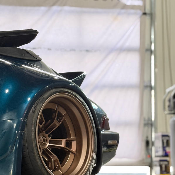 Close-up of a car wheel with a visible 'divine DESIGN' banner in the background.