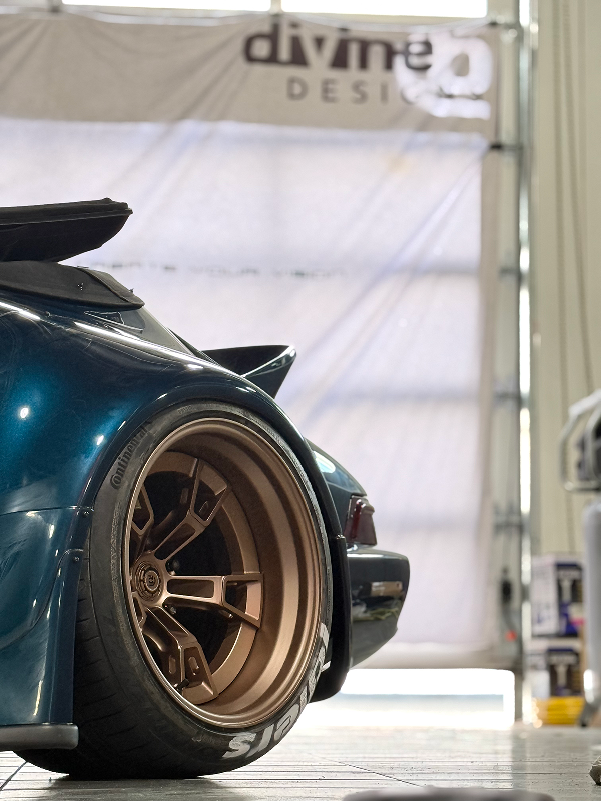 Close-up of a car wheel with a visible 'divine DESIGN' banner in the background.