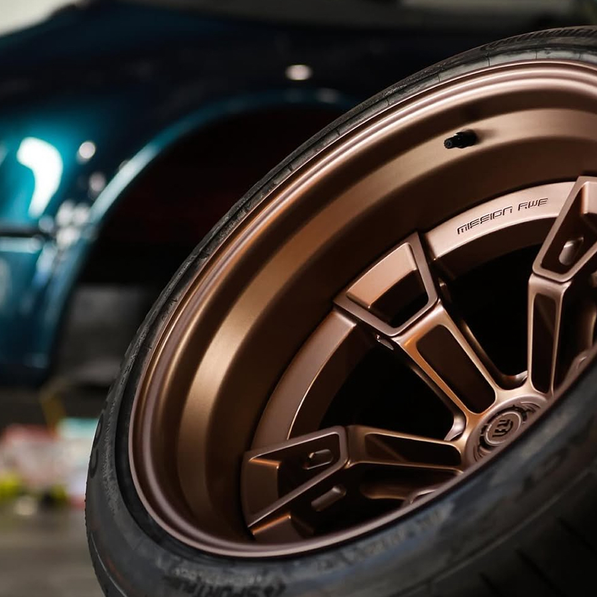 Close-up of a car wheel with a detailed rim design, blurred background