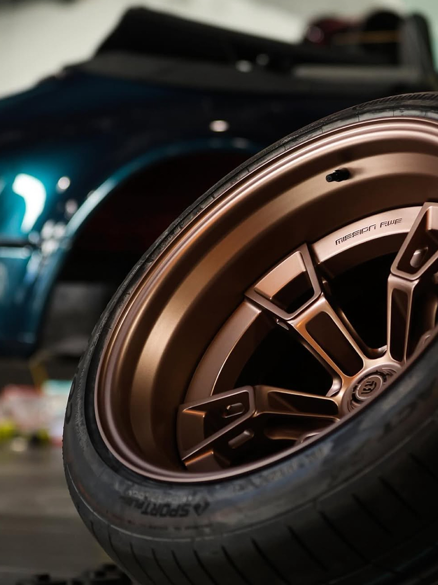 Close-up of a car wheel with a detailed rim design, blurred background