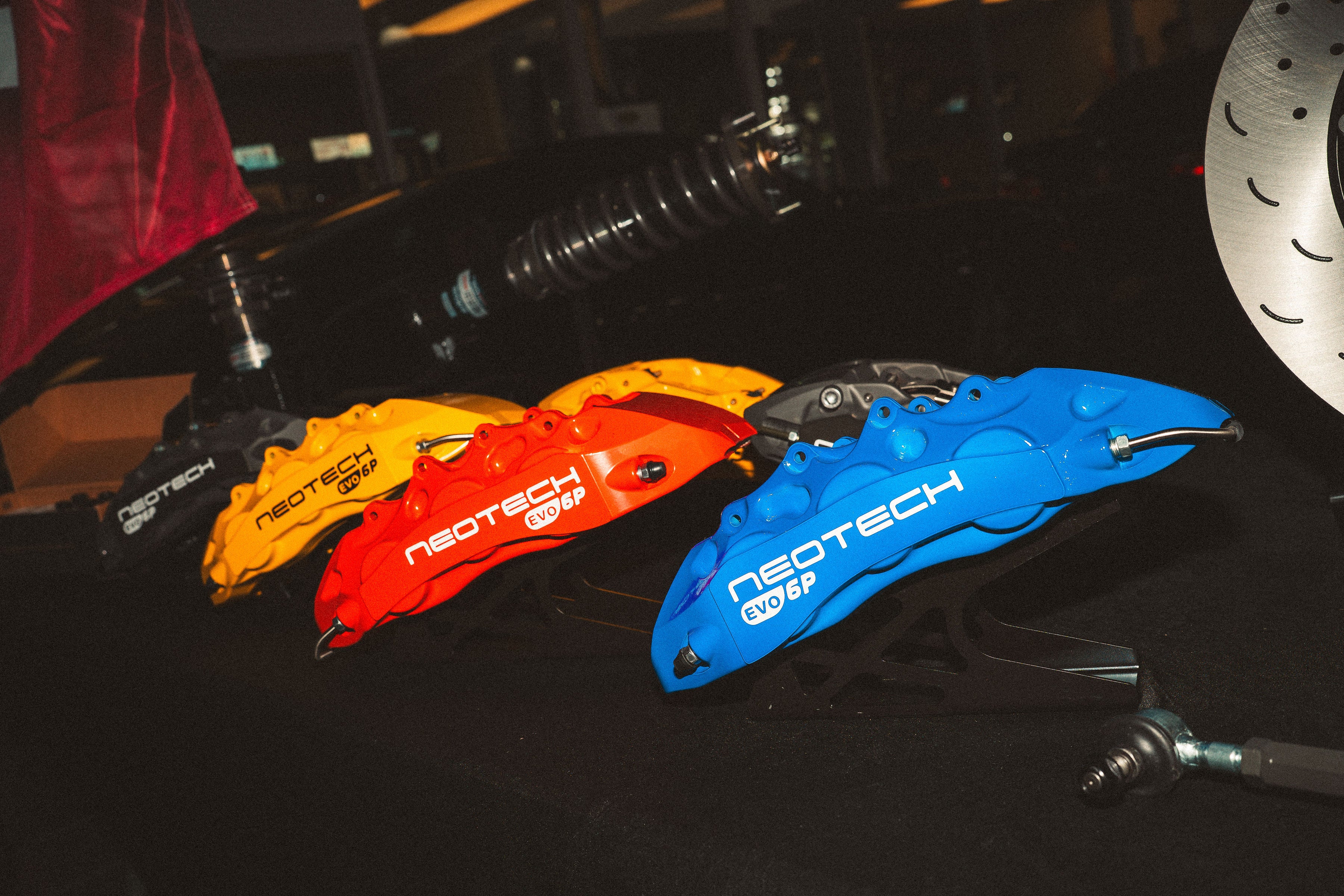 Four colorful brake calipers with 'Neotech' branding on a dark surface.