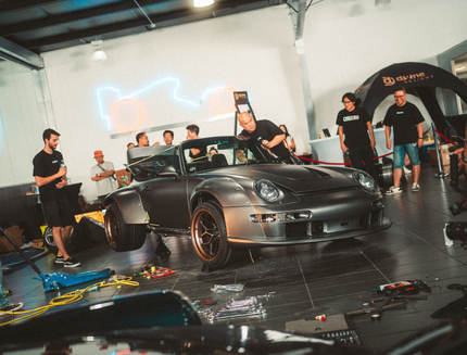 Car on a lift in a garage with people around