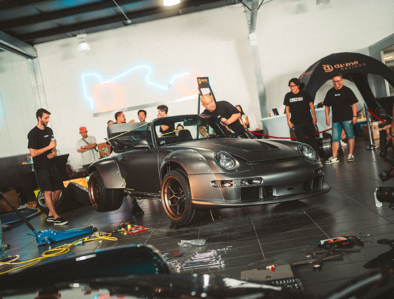Car on a lift in a garage with people around