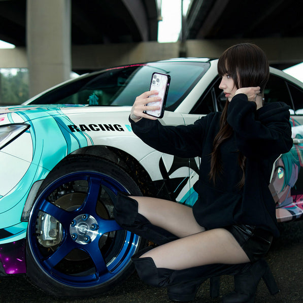 Woman taking a selfie next to a colorful racing car