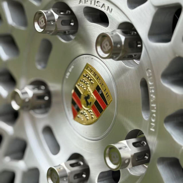 Close-up of a Porsche wheel rim with the brand logo and titanium lug nuts