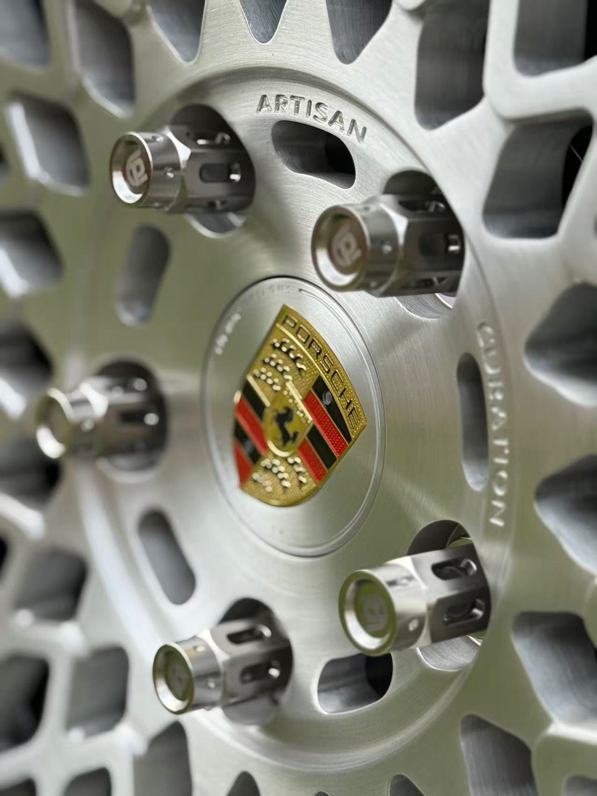 Close-up of a Porsche wheel rim with the brand logo and titanium lug nuts