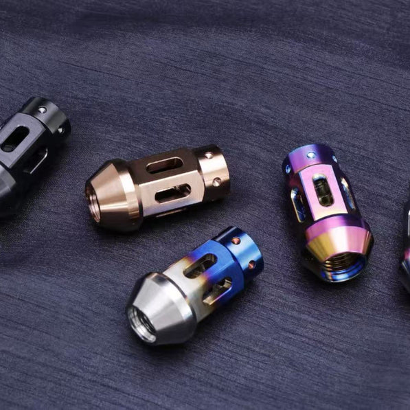 Five titanium lug nuts in different colors on a dark surface