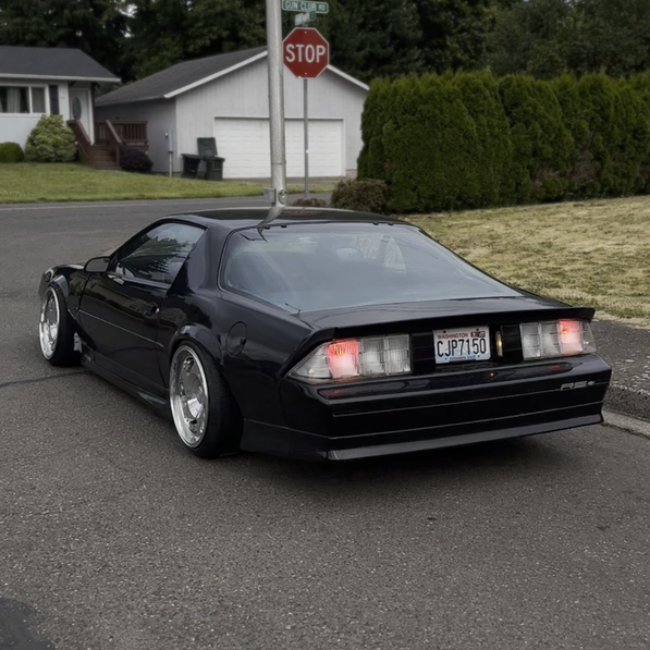 Black sports car on a residential street with a stop sign in the background