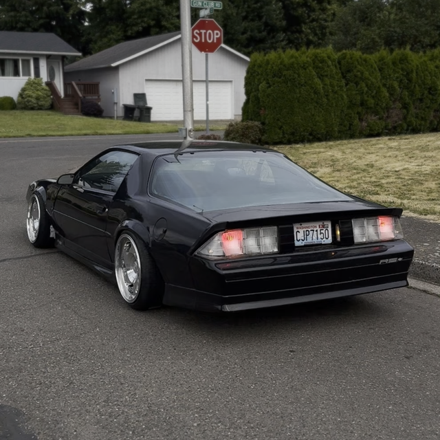 Black sports car on a residential street with a stop sign in the background