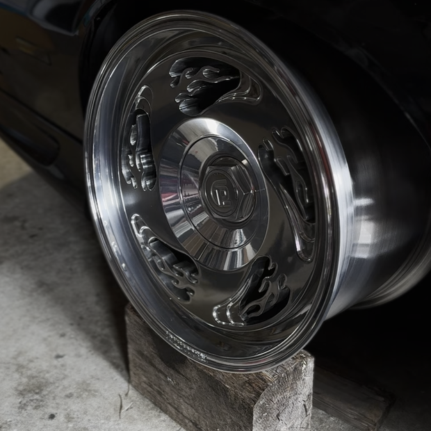 Close-up of a car wheel with flame design on a concrete surface