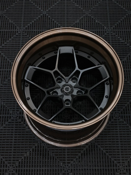 Close-up of a car wheel rim on a textured black surface