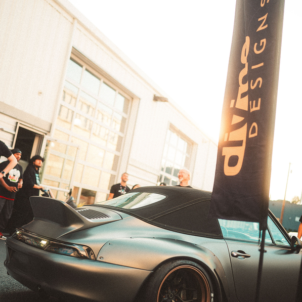 Silver sports car with a 'Divine Designs' banner in the background