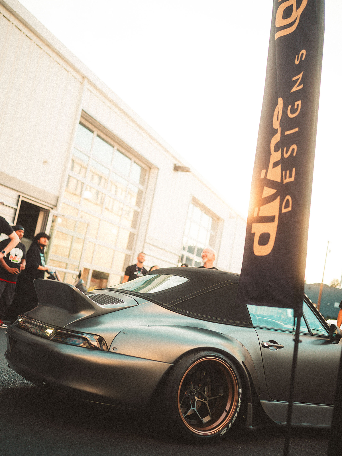 Silver sports car with a 'Divine Designs' banner in the background