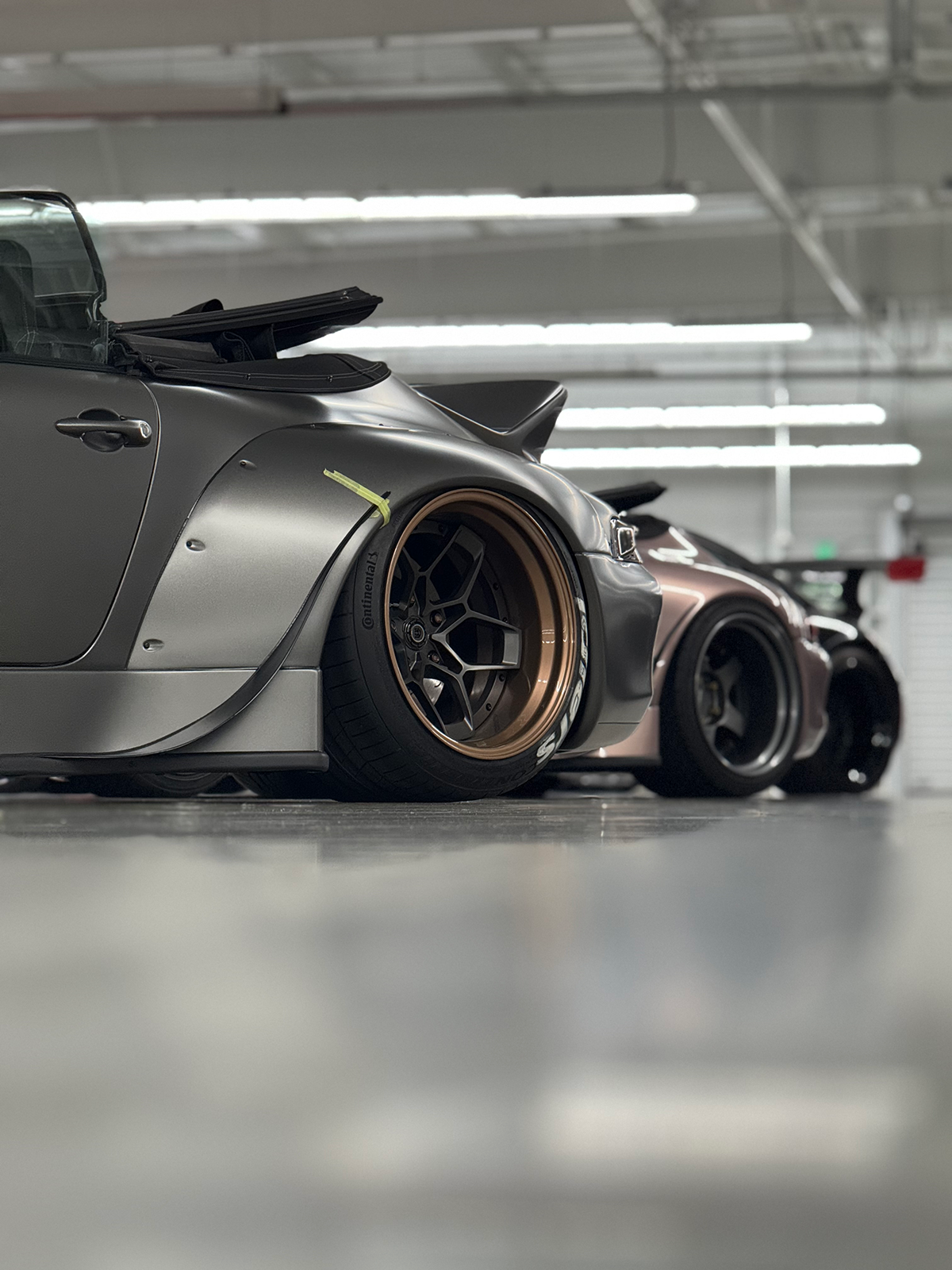 Gray sports car with custom wheels in a garage setting