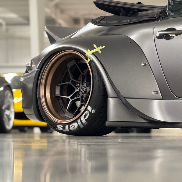 Close-up of a custom car wheel with branding in a garage setting