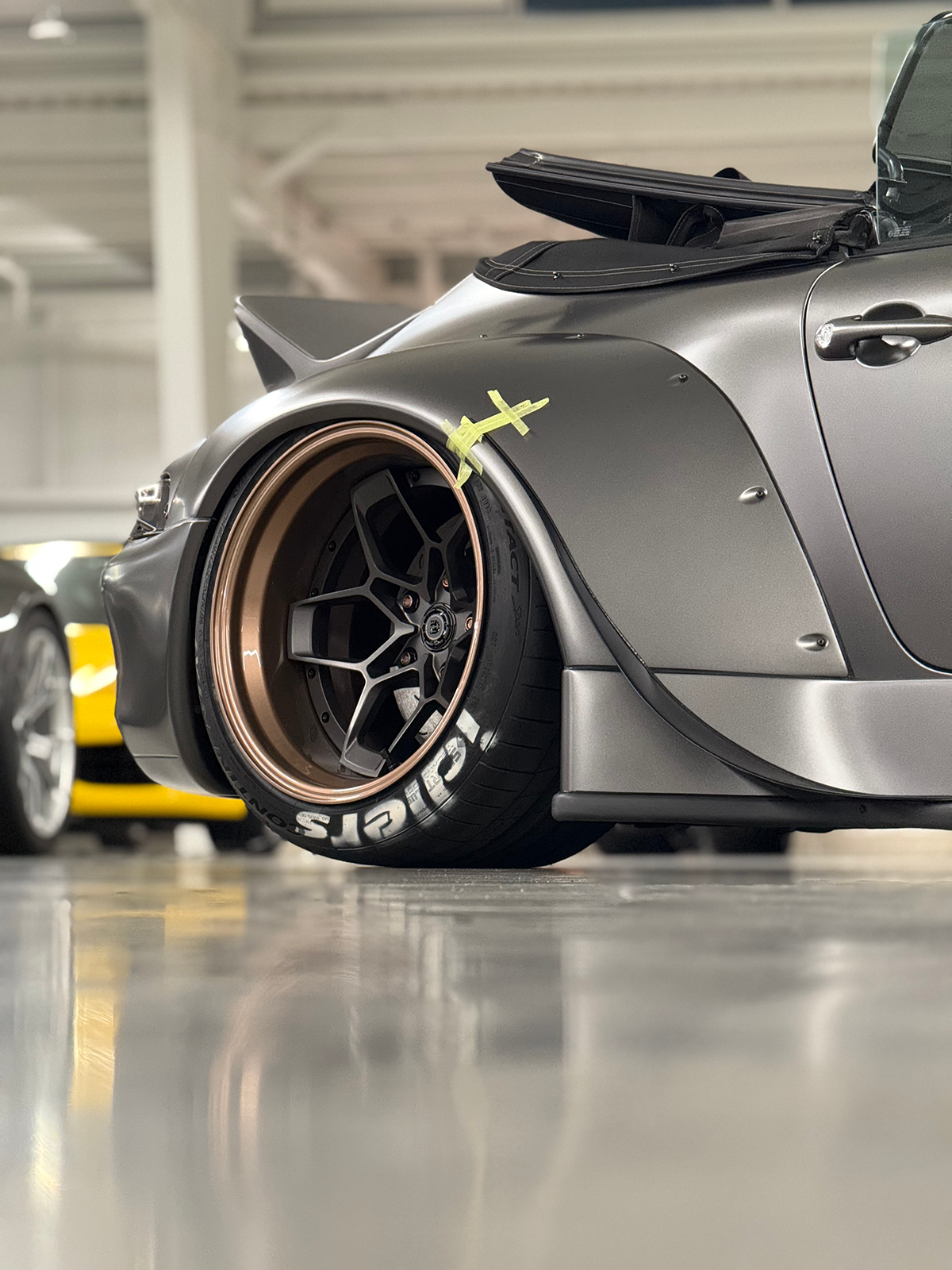 Close-up of a custom car wheel with branding in a garage setting