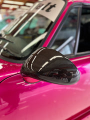 Close-up image of a one-piece seamless carbon fiber aero mirror for Porsche vehicles, displayed on a red car.